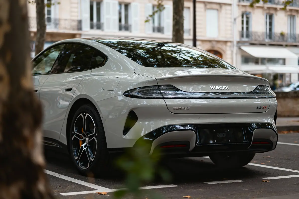 Voiture électrique SUV Haval S7 grise, stationnée, vue arrière, entourée d'arbres dans un espace urbain.