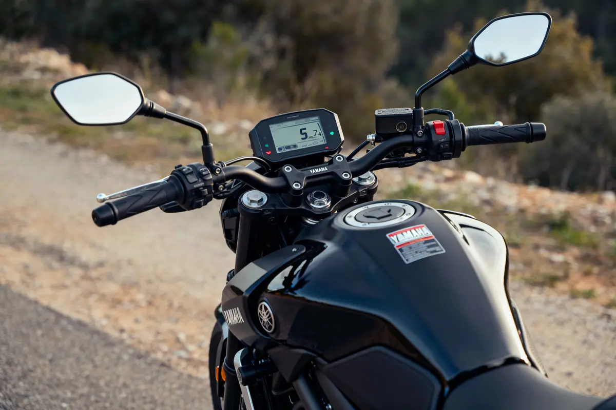 Guidon de moto Yamaha noir avec tableau de bord numérique, sur route déserte en arrière-plan flou.