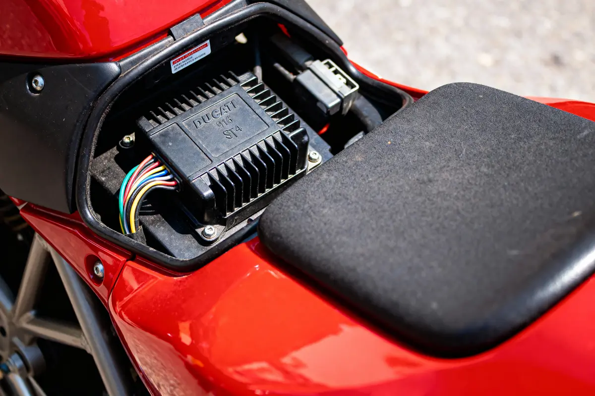 Électronique de moto Ducati rouge visible sous le siège, avec câblage coloré.