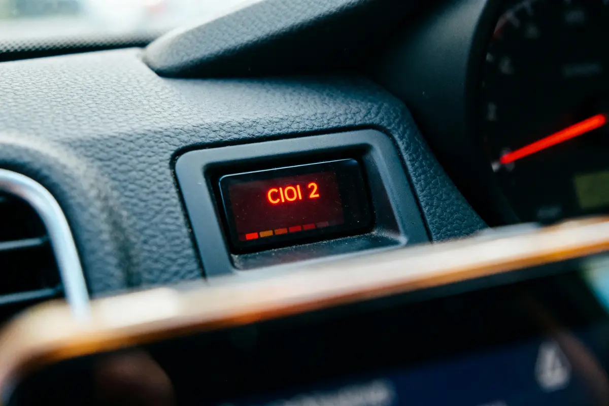 Écran de tableau de bord de voiture affichant "Clio 2" en rouge, intérieur du véhicule.