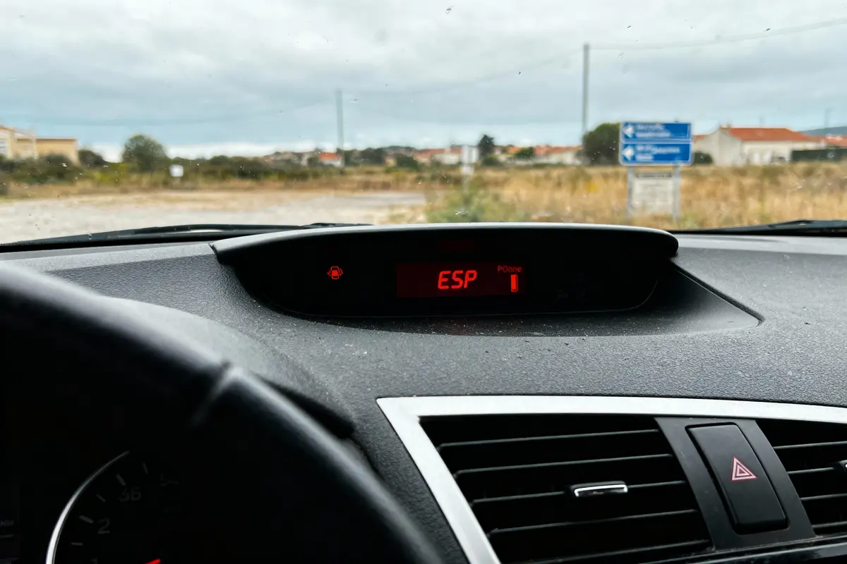 Tableau de bord de voiture affichant "ESP 1", avec paysage extérieur flou et panneau indicateur bleu.