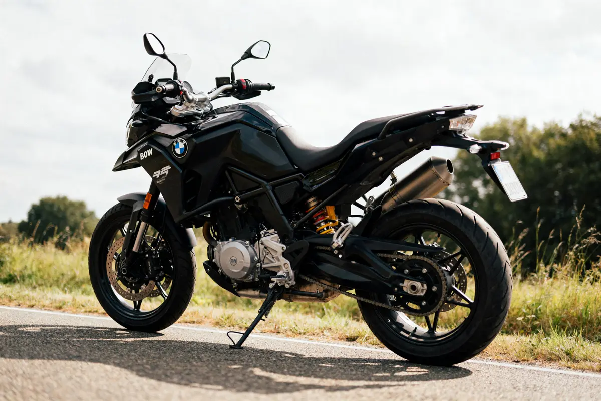 Moto noire BMW F 750 GS sur route, stationnée, ciel nuageux, paysage verdoyant en arrière-plan.