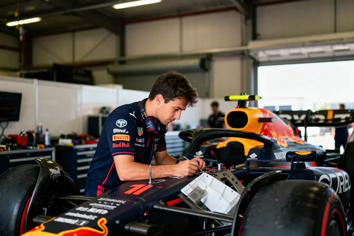 Jeune homme travaillant sur une voiture de course Red Bull dans un garage.