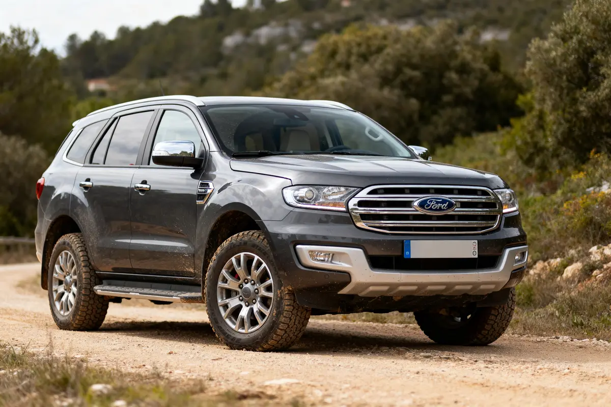 SUV gris de la marque Ford sur chemin de terre, entouré de végétation.
