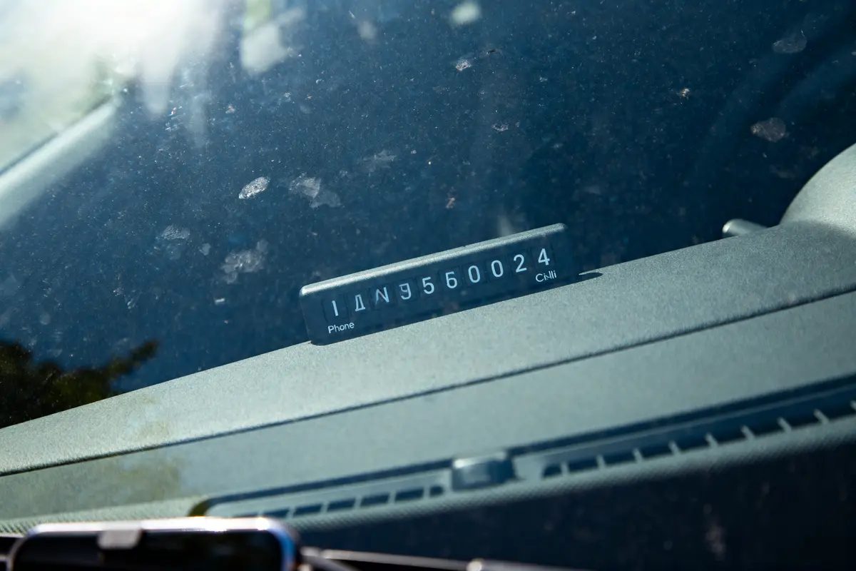 Plaque de téléphone amovible avec numéro visible sur tableau de bord d'une voiture.