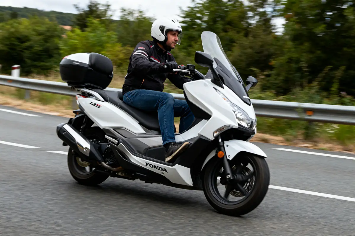 Pilote en mouvement sur Honda Forza 125 vitesse maximale sur route dégagée