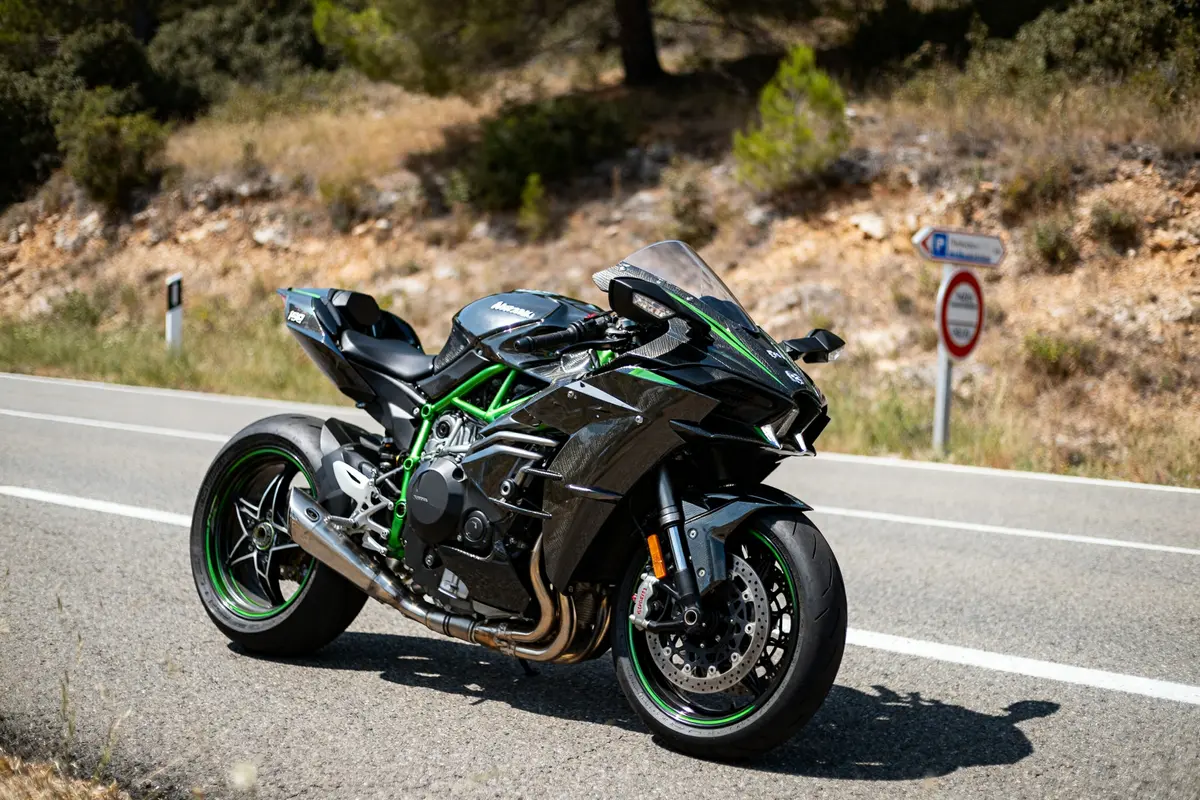 Moto Ninja H2R noire sur route ensoleillée entourée de nature verdoyante