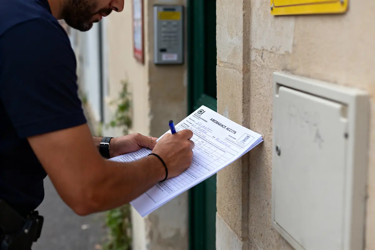 Homme en train de remplir un constat de voiture contre un mur extérieur beige