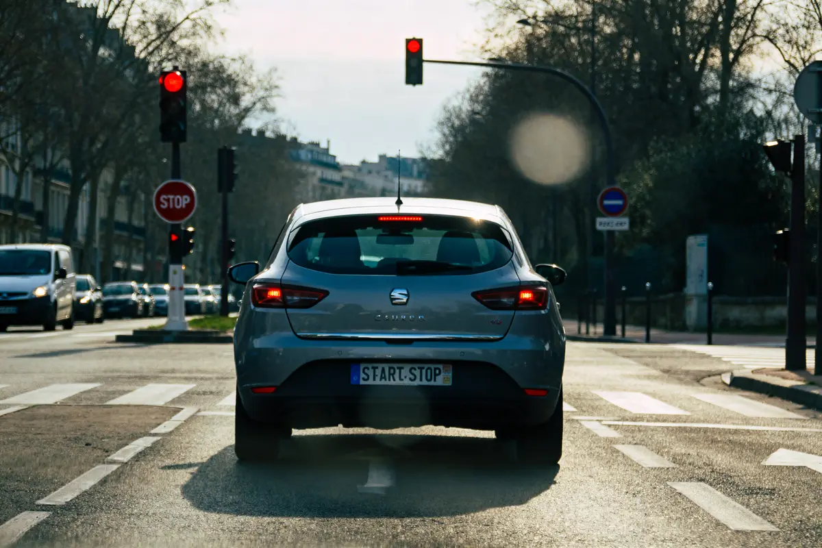 Une voiture s'arrête à un feu rouge avec plaque start and stop.