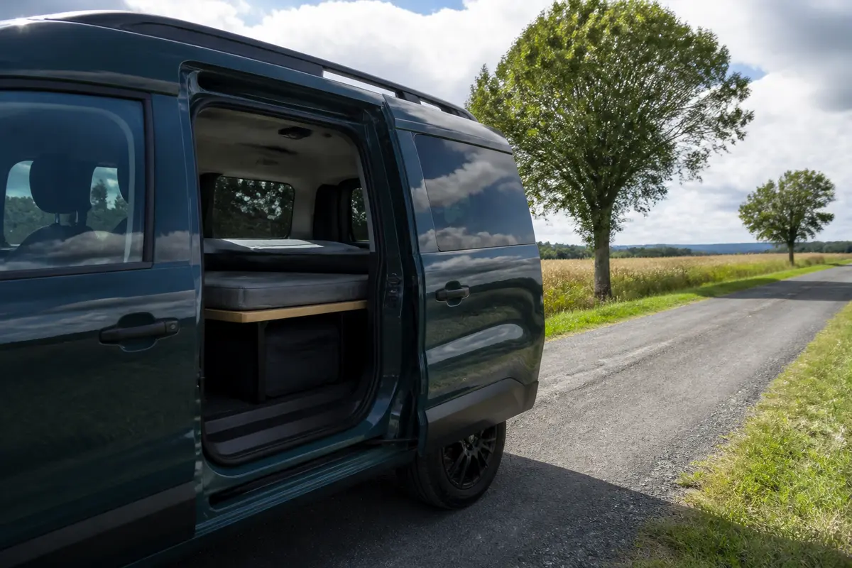 Vue latérale d'un Dacia van aménagé sur une route de campagne ensoleillée