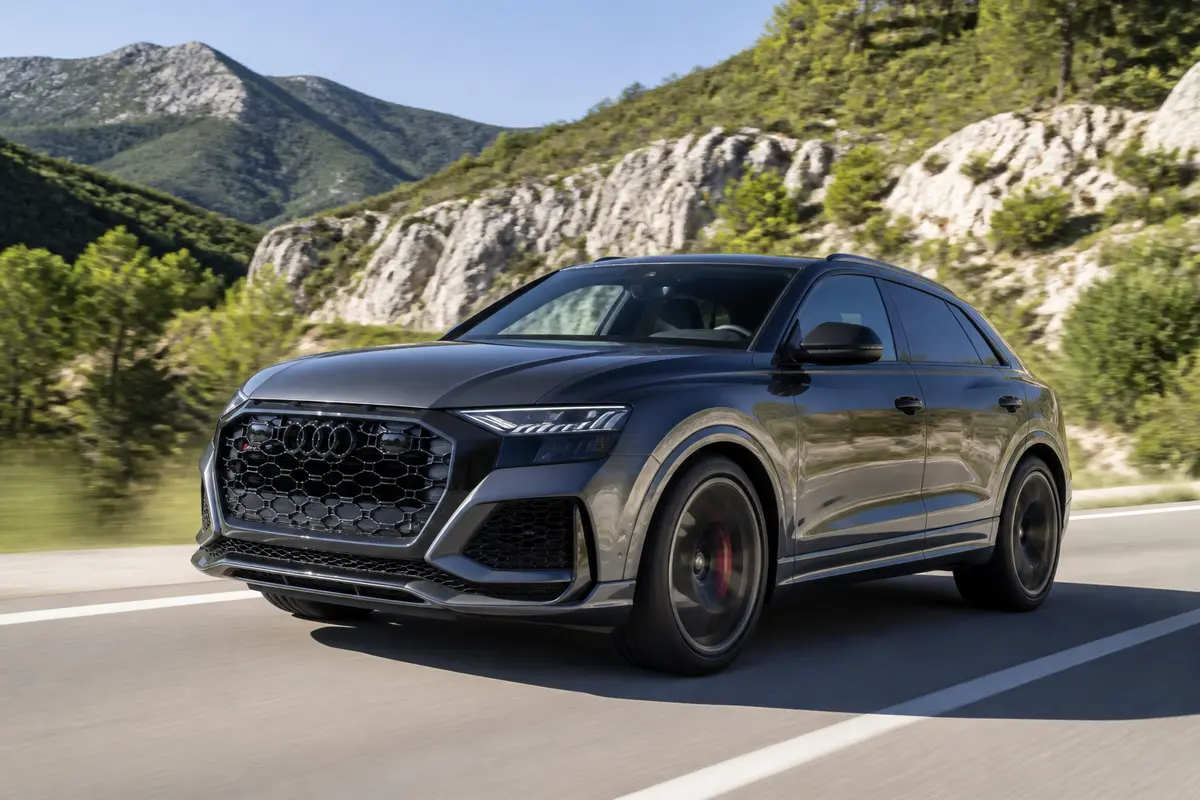 SUV Audi RSQ8 roulant sur route montagneuse avec paysage naturel en arrière-plan