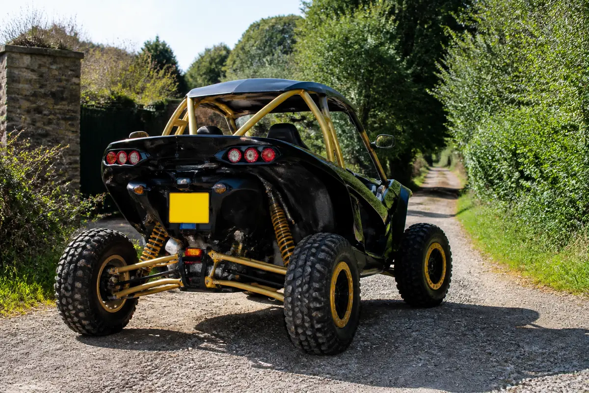 Buggy homologué noir et jaune sur chemin forestier entouré de végétation luxuriante