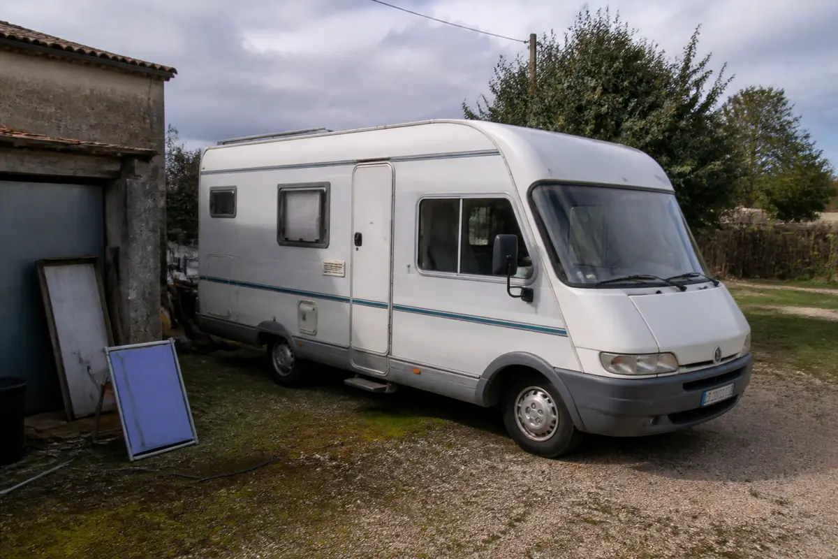 Camping-car blanc stationné à vendre pour cause de décès ou divorce dans jardin verdoyant