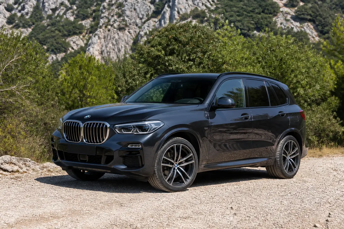 SUV noir en extérieur devant montagne, modèle x5 élégant et puissant sur terrain gravillonné
